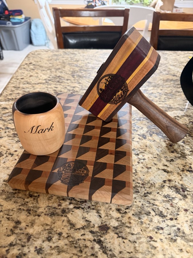 Specialty wood pieces including a wooden whiskey glass, mallet, and patterned board